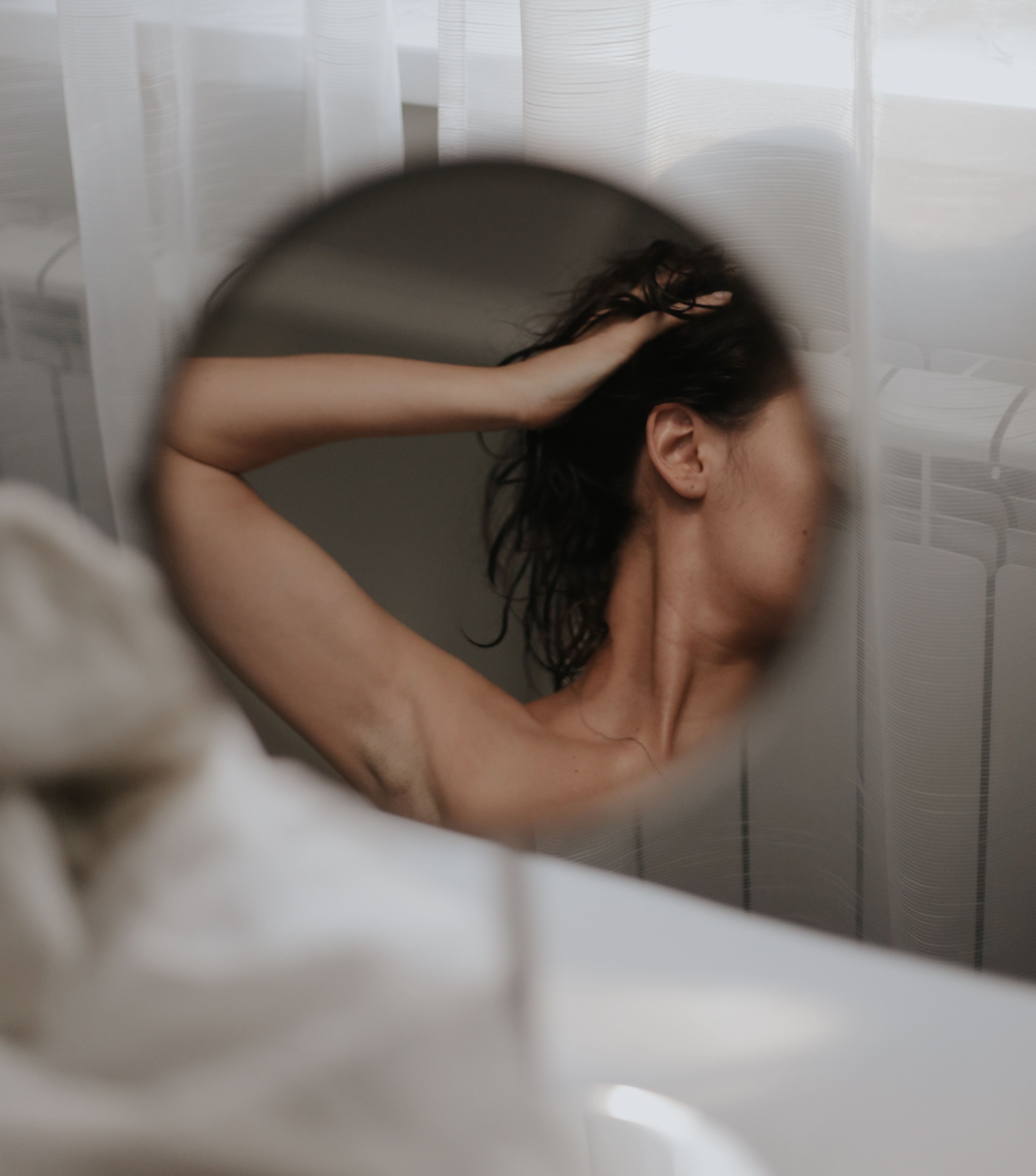Person in a bathroom running their hand through wet hair