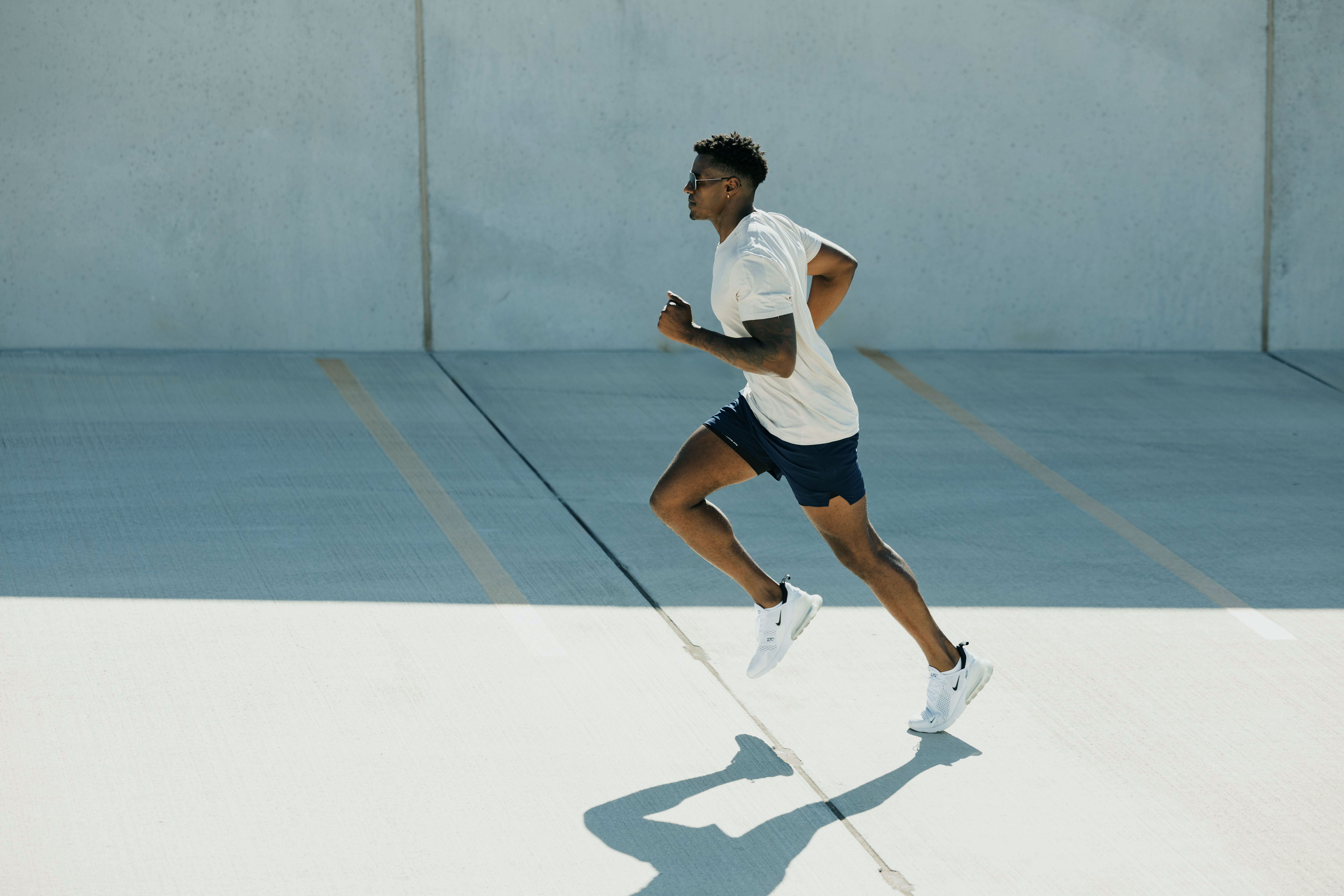 A runner moving across a sunlit concrete surface